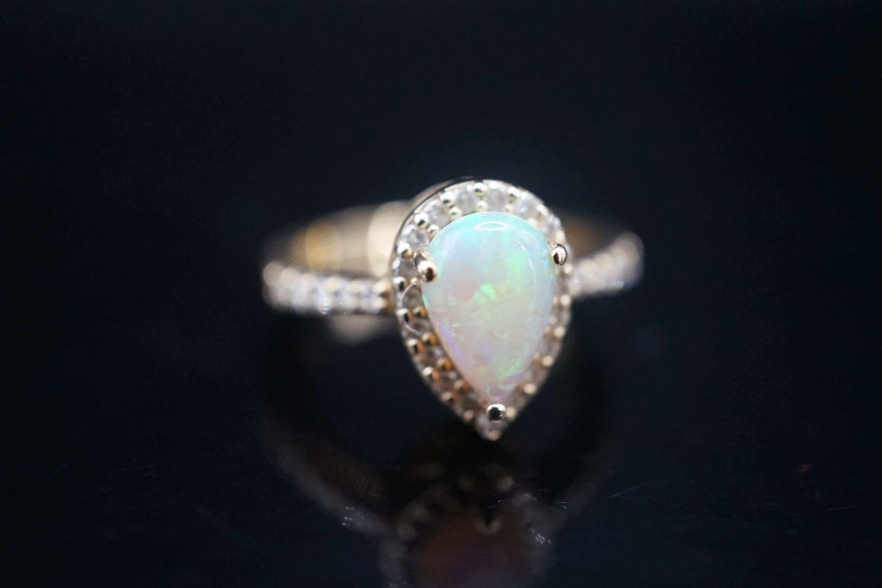 A modern 14k yellow meta, white opal and diamond set pear shape cluster ring, with diamond set shoulders, size K, gross weight 4.3 grams.